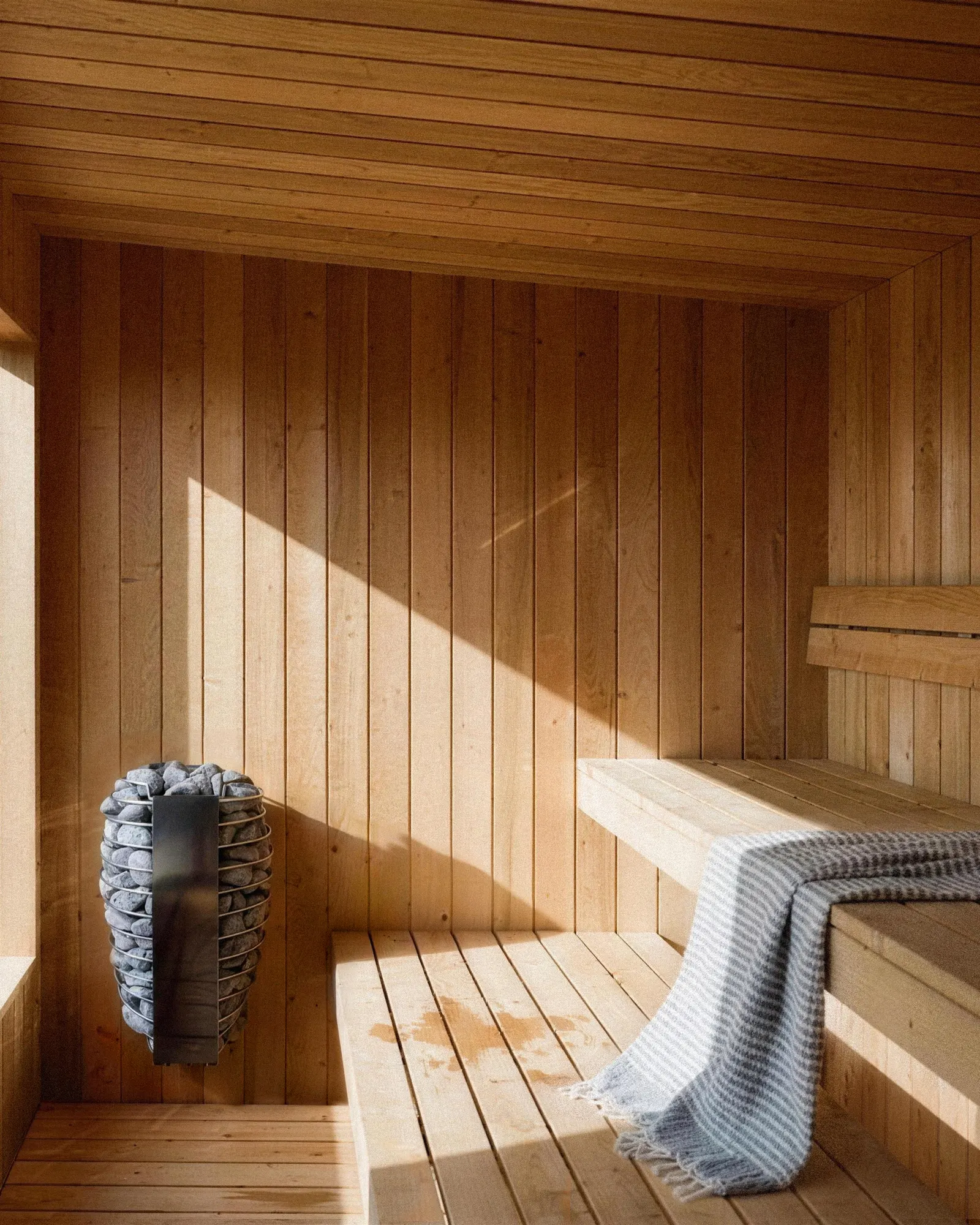 Sunlit sauna interior with heater and bench